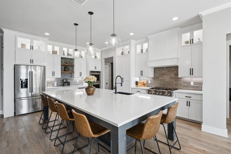 Dual tone kitchen with a kitchen breakfast bar, stainless steel appliances, a spacious island, light wood-type flooring, and two tone cabinets