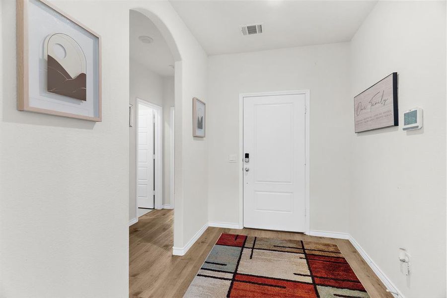 Foyer with baseboards, visible vents, arched walkways, and light wood-type flooring