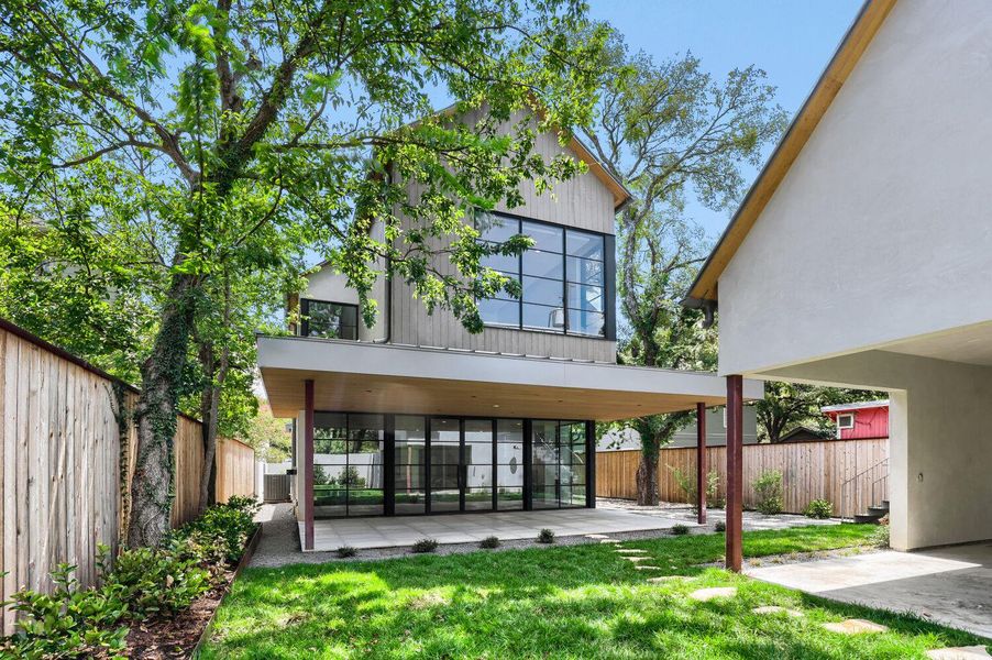 Modern architecture showcases towering windows and a spacious covered patio, perfect for outdoor living.