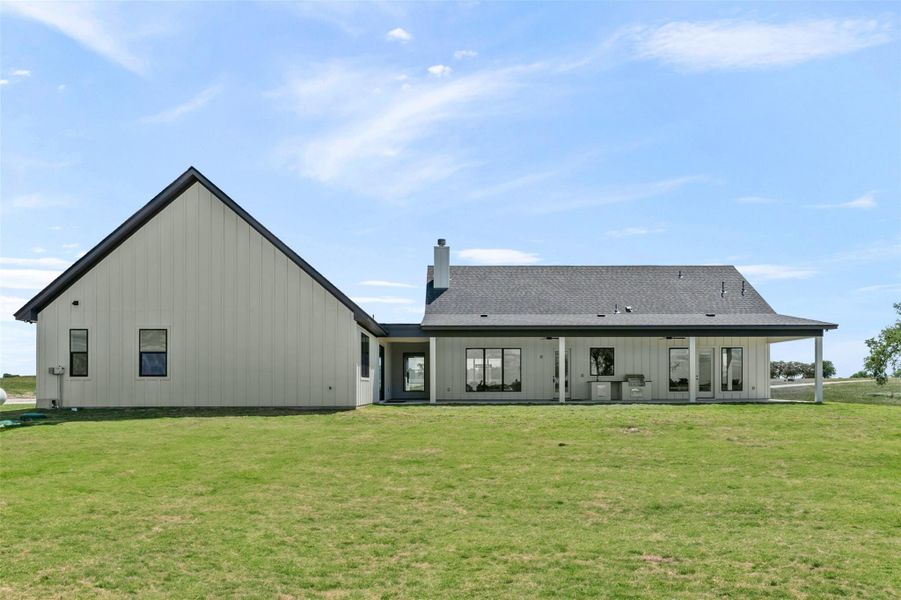Back of property featuring a yard, board and batten siding, and a chimney Back of property featuring a yard, board and batten siding, and a chimney
