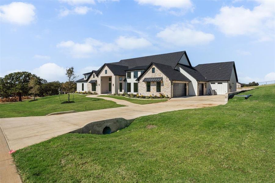 View of front of home featuring stone siding, concrete driveway, a front lawn, a shingled roof, and a garage View of front of home featuring stone siding, concrete driveway, a front lawn, a shingled roof, and a garage