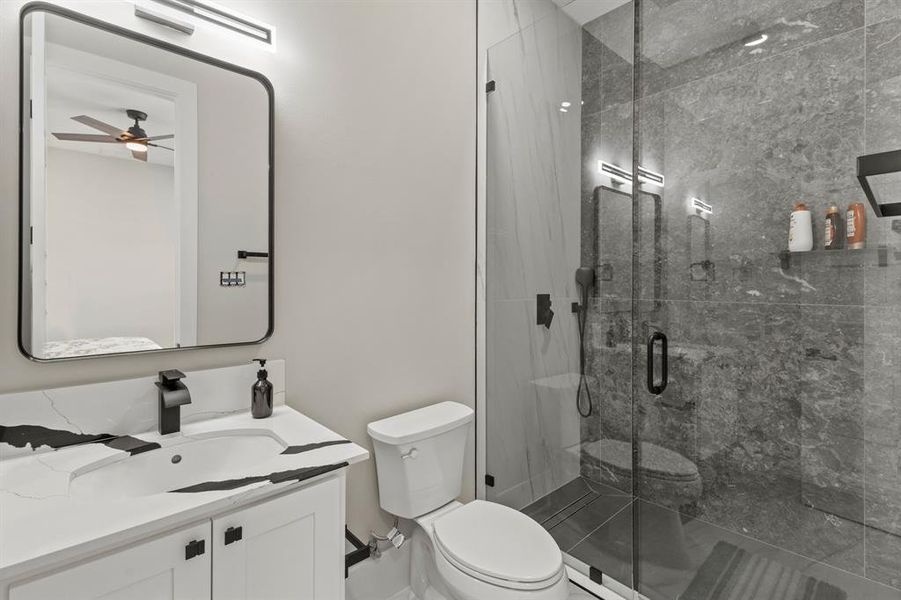 Bathroom featuring vanity, a marble finish shower, and ceiling fan