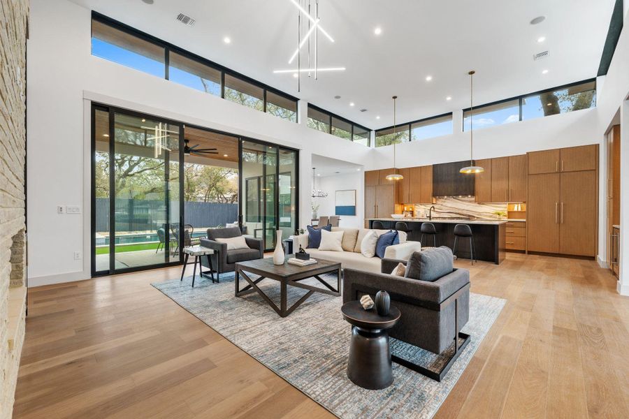 Living area with a high ceiling, light wood-style flooring, recessed lighting
