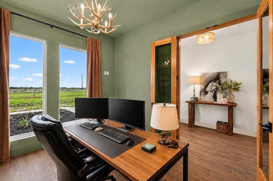 Room featuring two large windows, wood-finish flooring, a decorative antler-style chandelier, and double French doors with glass panels