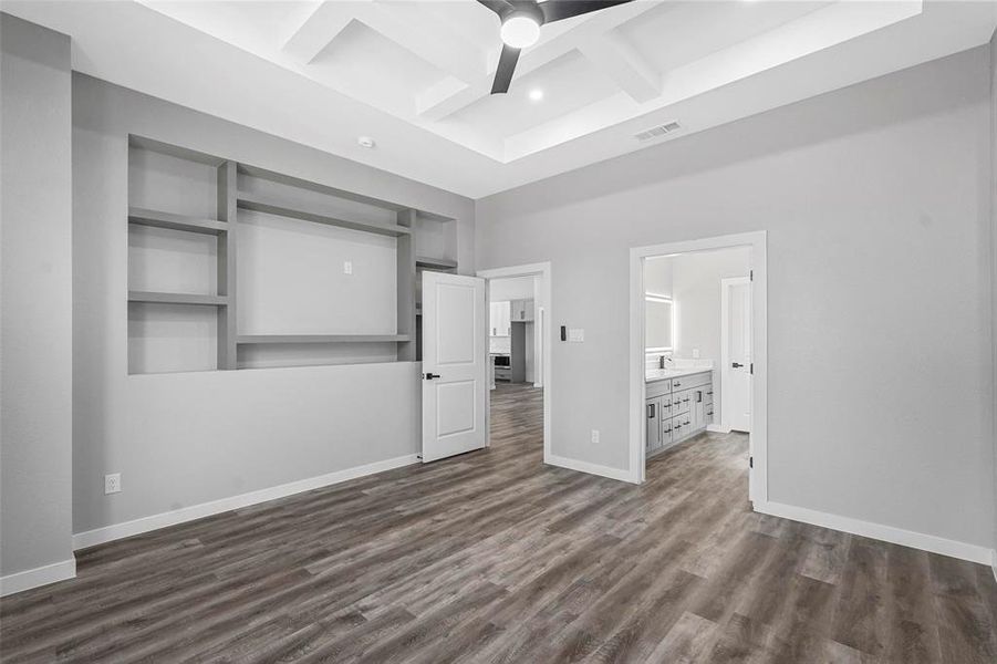 Unfurnished bedroom with dark hardwood / wood-style flooring, coffered ceiling, connected bathroom, beamed ceiling, and ceiling fan