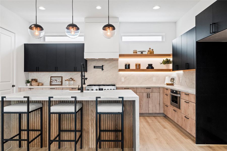 A magazine-worthy kitchen featuring a 36-inch, 6-burner Bosch gas range with vent hood and pot filler. European-style two-tone cabinetry pairs with floating shelves illuminated by integrated LED lighting. A magazine-worthy kitchen featuring a 36-inch, 6-burner Bosch gas range with vent hood and pot filler. European-style two-tone cabinetry pairs with floating shelves illuminated by integrated LED lighting.
