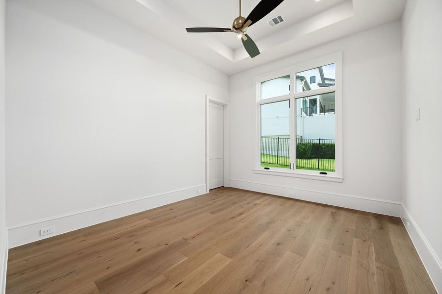 Bright hardwood floors and a modern ceiling fan elevate this tranquil bedroom space.