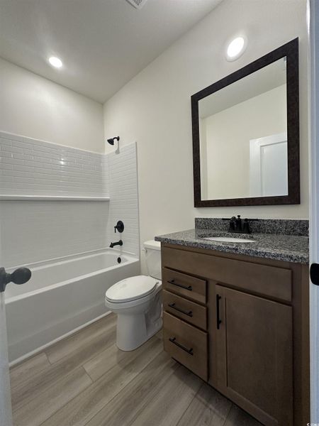 Full bath featuring tub / shower combination, vanity, light wood-style floors, and recessed lighting