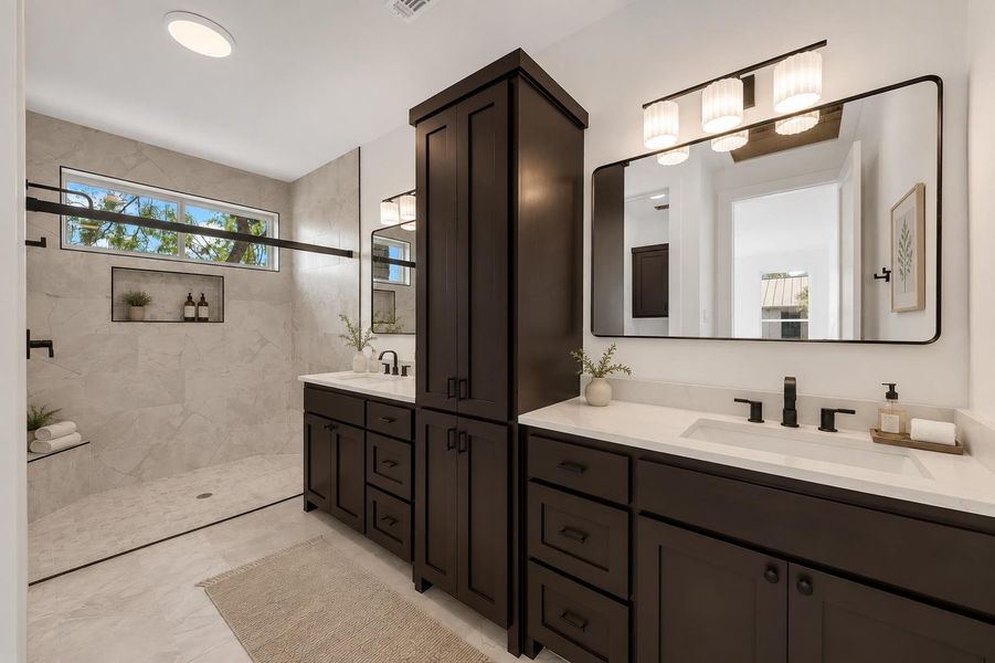 Custom dark wood cabinetry accents this tiled master bathroom with dual vanities and walk-in shower.