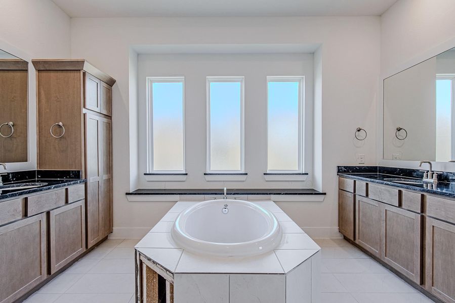 Another angle of the primary bathroom featuring soaking tub and separate vanity areas.