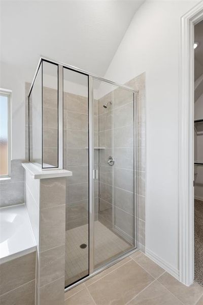 Bathroom featuring a bath, a shower stall, light tile patterned floors, vaulted ceiling, and a walk in closet