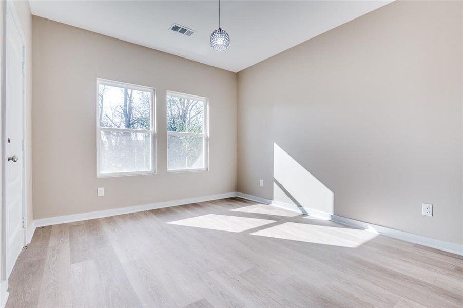 Spare room with light wood-style flooring, baseboards, and visible vents