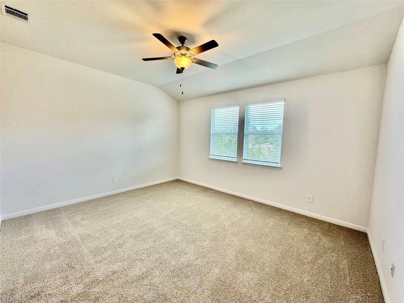 Carpeted spare room featuring lofted ceiling and ceiling fan