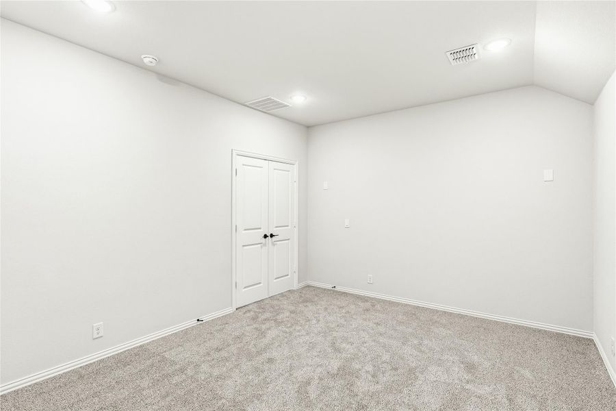 Empty bedroom with gray carpet, white walls, and double closet doors