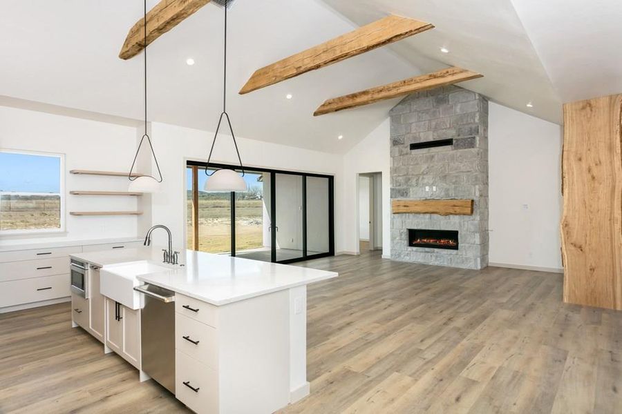 Kitchen featuring pendant lighting, white cabinets, open shelves, a center island with sink, and light wood-style flooring Kitchen featuring pendant lighting, white cabinets, open shelves, a center island with sink, and light wood-style flooring