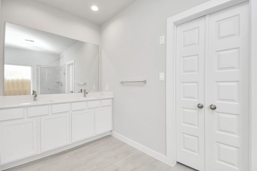 Elevate your daily routine at the elegant vanity, now equipped with double sinks, light countertops, modern hardware, and beautiful recessed lights. Sample photo of completed home with similar floor plan. Actual colors and selections may vary.