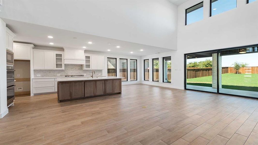 Kitchen with light hardwood / wood-style flooring, a center island with sink, and white cabinets