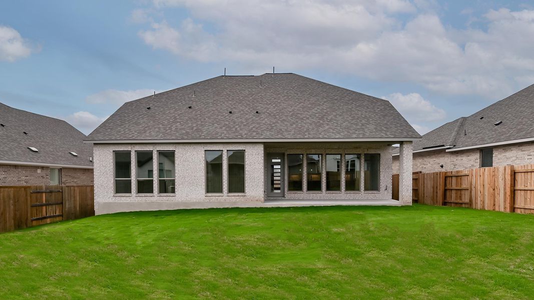Back of property featuring a yard, brick siding, roof with shingles, and a fenced backyard