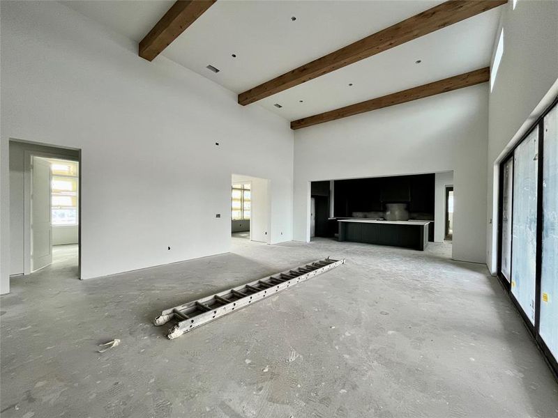 Unfurnished living room featuring beamed ceiling and a high ceiling