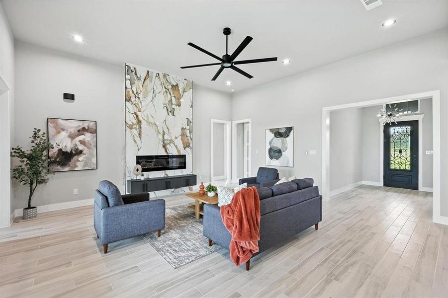 Living room with light wood-style flooring, recessed lighting, a ceiling fan, a chandelier, and a towering ceiling Living room with light wood-style flooring, recessed lighting, a ceiling fan, a chandelier, and a towering ceiling