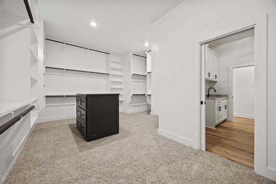 Walk in closet with light carpet and a sink