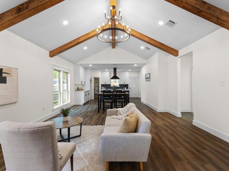 Living area with hanging lights, dark wood-style flooring, and beam ceiling