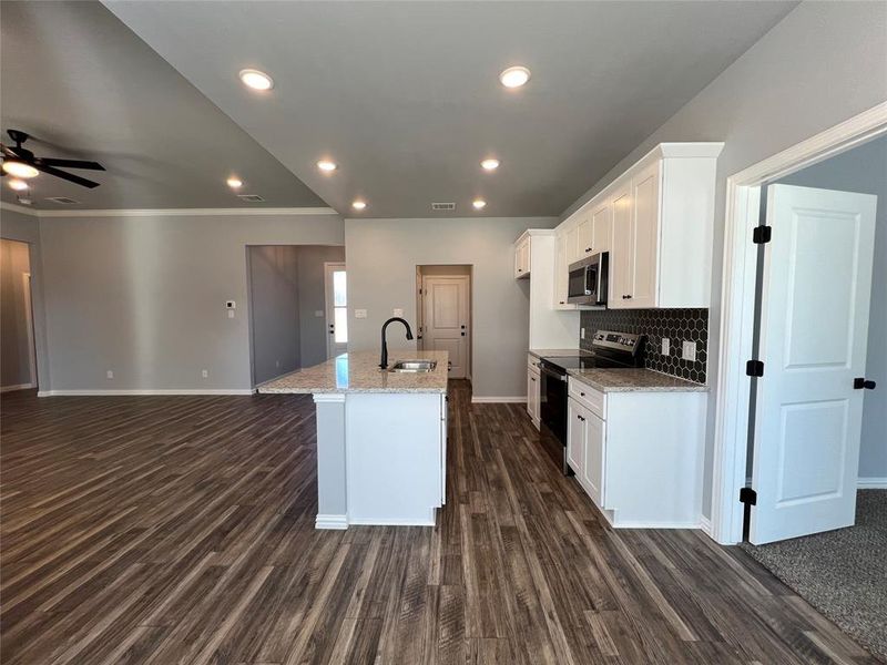 Kitchen featuring light stone countertops, stainless steel appliances, dark wood-type flooring, sink, and white cabinets