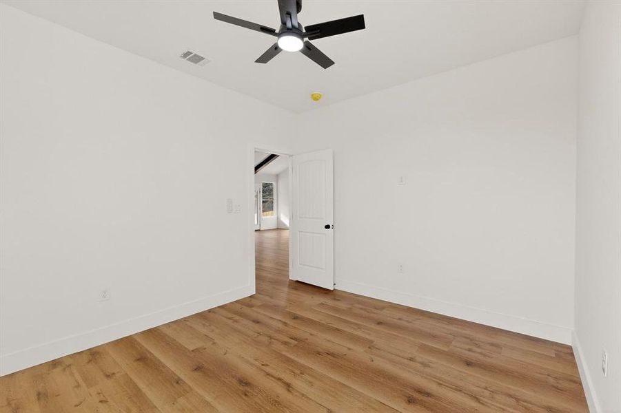 Empty room featuring light wood-style flooring and a ceiling fan Empty room featuring light wood-style flooring and a ceiling fan