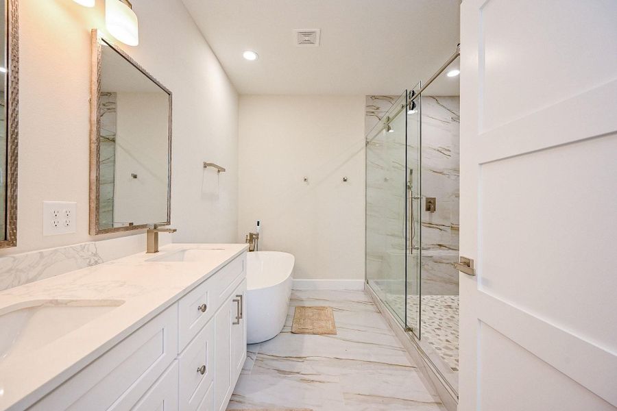Spa-inspired primary bathroom featuring dual vanities, sleek finishes, and a spacious glass shower