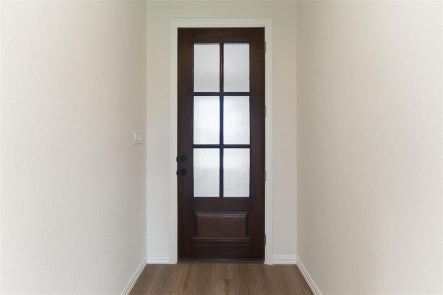 Doorway with wood finished floors and baseboards