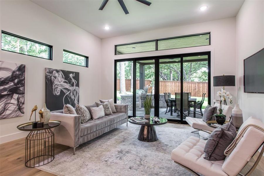 Living room featuring ceiling fan, wood-type flooring, and a high ceiling