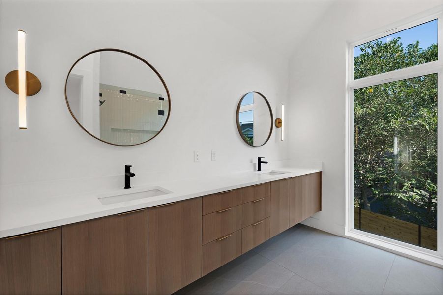 Full bath with double vanity, dark tile patterned flooring, and a shower
