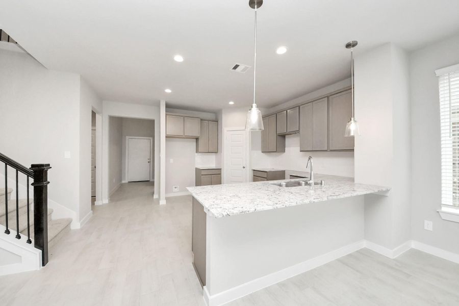 Discover another perspective of this stunning kitchen, generously appointed with an abundance of counter space! Sample photo of completed home with similar floor plan. Actual colors and selections may vary. Discover another perspective of this stunning kitchen, generously appointed with an abundance of counter space! Sample photo of completed home with similar floor plan. Actual colors and selections may vary.