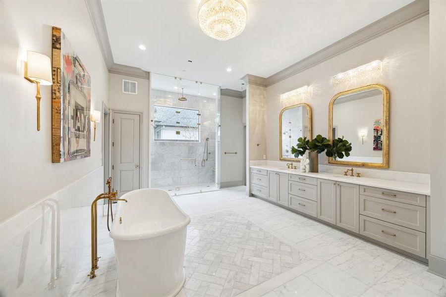 Featuring a stunning freestanding tub with gold fixtures, dual vanities with gilded mirrors, and a walk-in shower surrounded by marble, every detail has been thoughtfully designed.