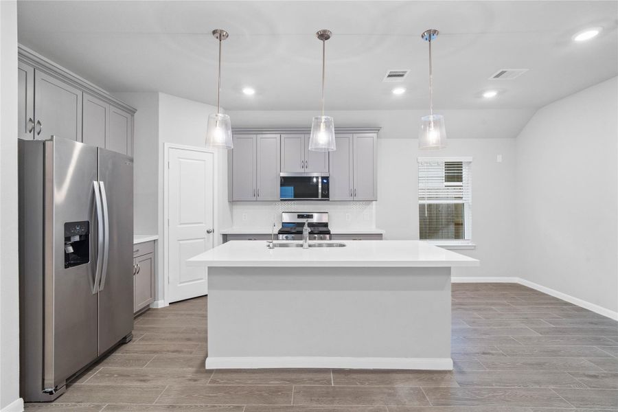 The extended quartz countertop creates a convenient breakfast bar, providing a casual and inviting space where stools can be added for quick meals or long conversations.