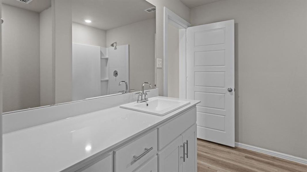 Bathroom with vanity, wood finished floors, baseboards, a shower, and recessed lighting Bathroom with vanity, wood finished floors, baseboards, a shower, and recessed lighting