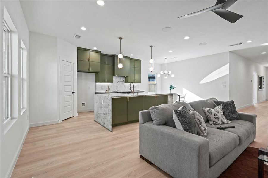 Living area with light wood-style flooring, recessed lighting, a ceiling fan, healthy amount of natural light, and a chandelier