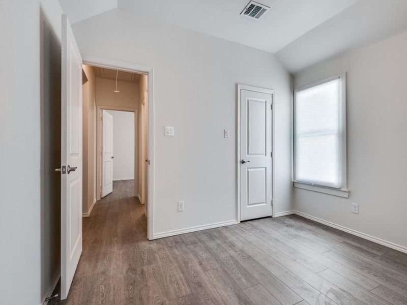 Unfurnished bedroom featuring hardwood / wood-style floors and lofted ceiling