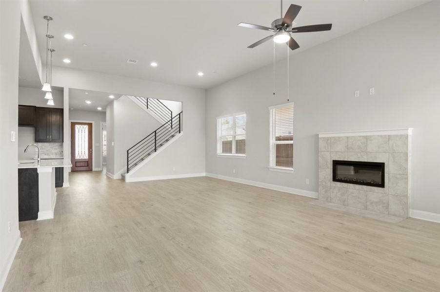 Unfurnished living room featuring light wood-style flooring, healthy amount of natural light, a fireplace, a ceiling fan, and recessed lighting Unfurnished living room featuring light wood-style flooring, healthy amount of natural light, a fireplace, a ceiling fan, and recessed lighting