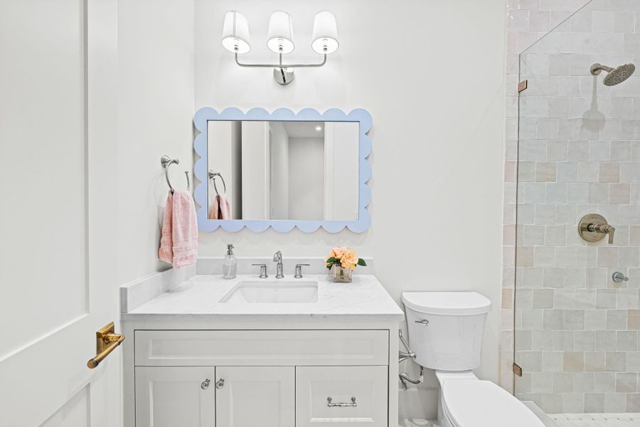 Serving secondary bedroom #3, this en suite bath features a quartz countertop vanity w/ storage below & a Visual Comfort sconce. The shower offers a frameless glass enclosure, Zellige tile surround & a basketweave-patterned tile floor, paired w/ a quartz threshold & built-in niche. Clean, timeless finishes complete the space. Serving secondary bedroom #3, this en suite bath features a quartz countertop vanity w/ storage below & a Visual Comfort sconce. The shower offers a frameless glass enclosure, Zellige tile surround & a basketweave-patterned tile floor, paired w/ a quartz threshold & built-in niche. Clean, timeless finishes complete the space.