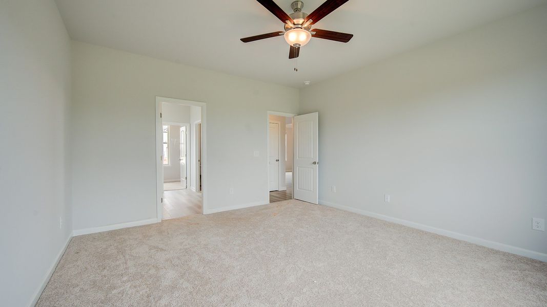 Meridian II primary suite with coffered ceiling, carpet flooring, and connected bath at Brighton in Locust Grove, GA.