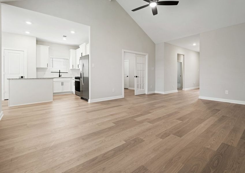Family room with a vaulted ceiling and double French doors that lead to a flex room. The kitchen is also shown.