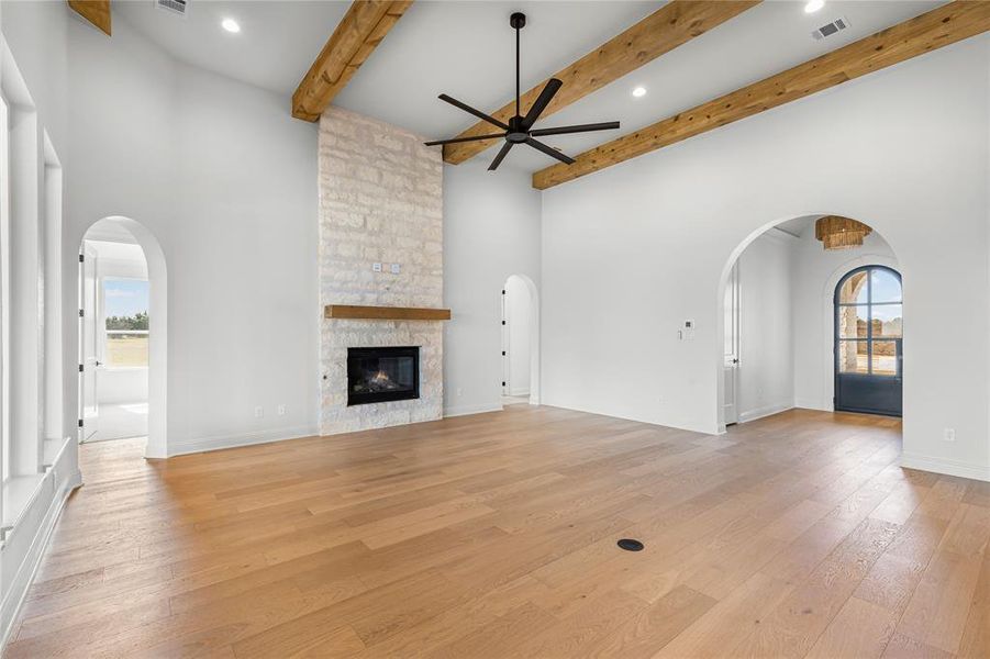 Unfurnished living room with arched walkways, ceiling fan, a fireplace, light wood-type flooring, and recessed lighting
