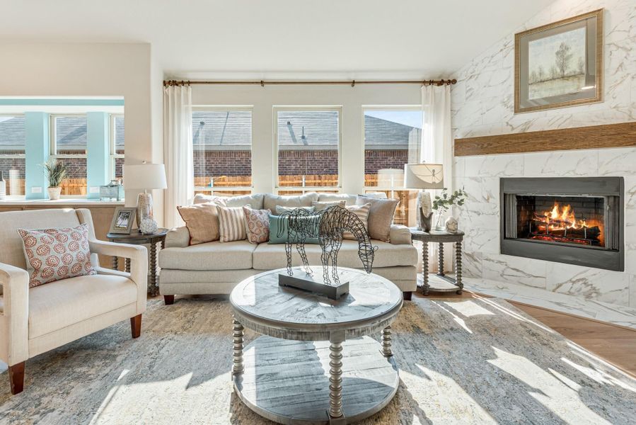 Living room with beige sofa, round coffee table, and marble tile fireplace with wood mantel