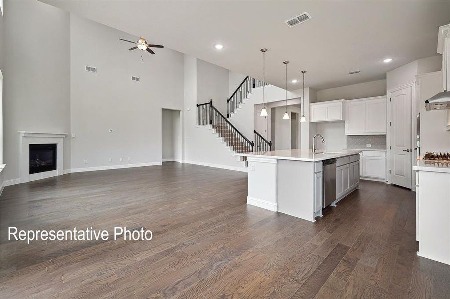 Spacious living area featuring high vaulted ceilings, a built-in fireplace with a white mantel, and wood-finish flooring