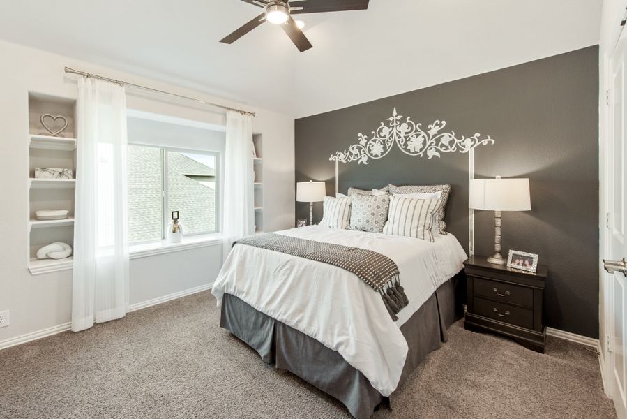 Bedroom with gray accent wall, built-in shelves, ceiling fan, and queen bed with white bedding
