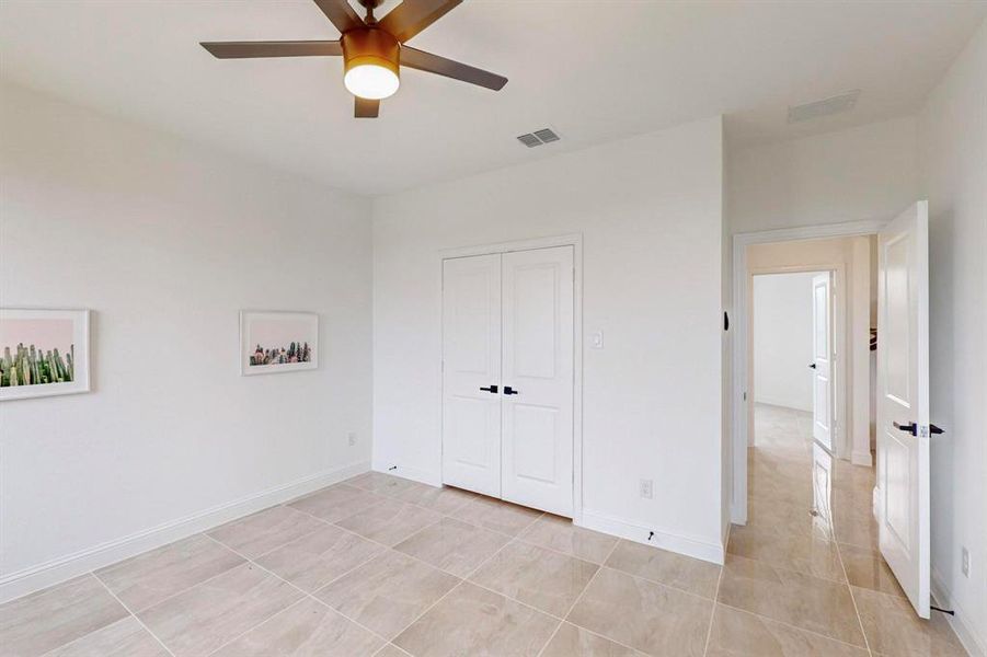 Unfurnished bedroom with light tile patterned floors, ceiling fan, and a closet