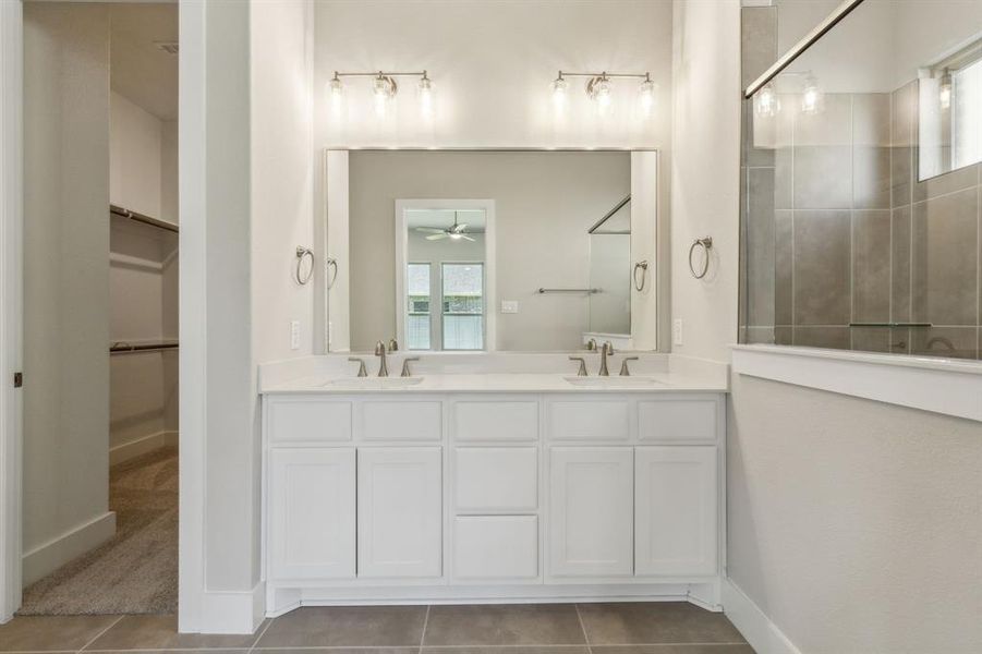 Bathroom with an enclosed shower, vanity, tile patterned floors, and ceiling fan