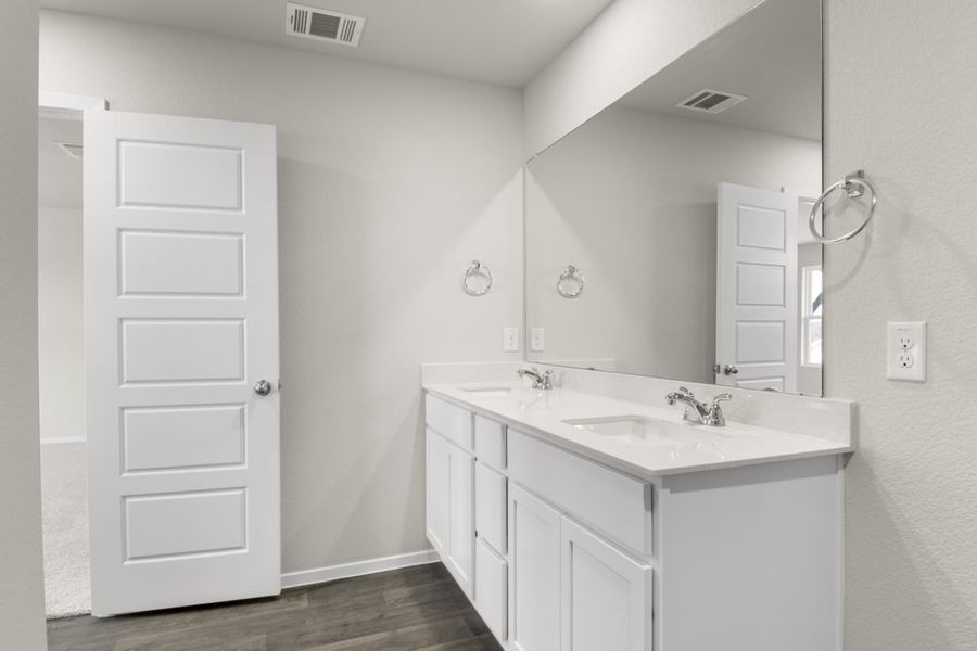 Image of primary bathroom with white cabinets with a mirror and vanity