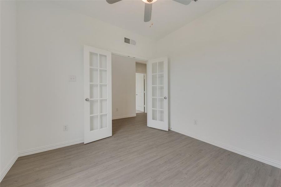 Spare room featuring french doors, light wood-type flooring, and ceiling fan